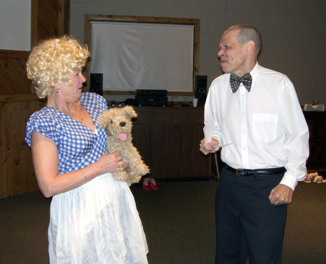 Arlene Merryman as Dorothy protects her little dog, Tito, from Bert Furioli as Mr. Gulp, who say the EPA has declared Tito a hazardous waste dumper.